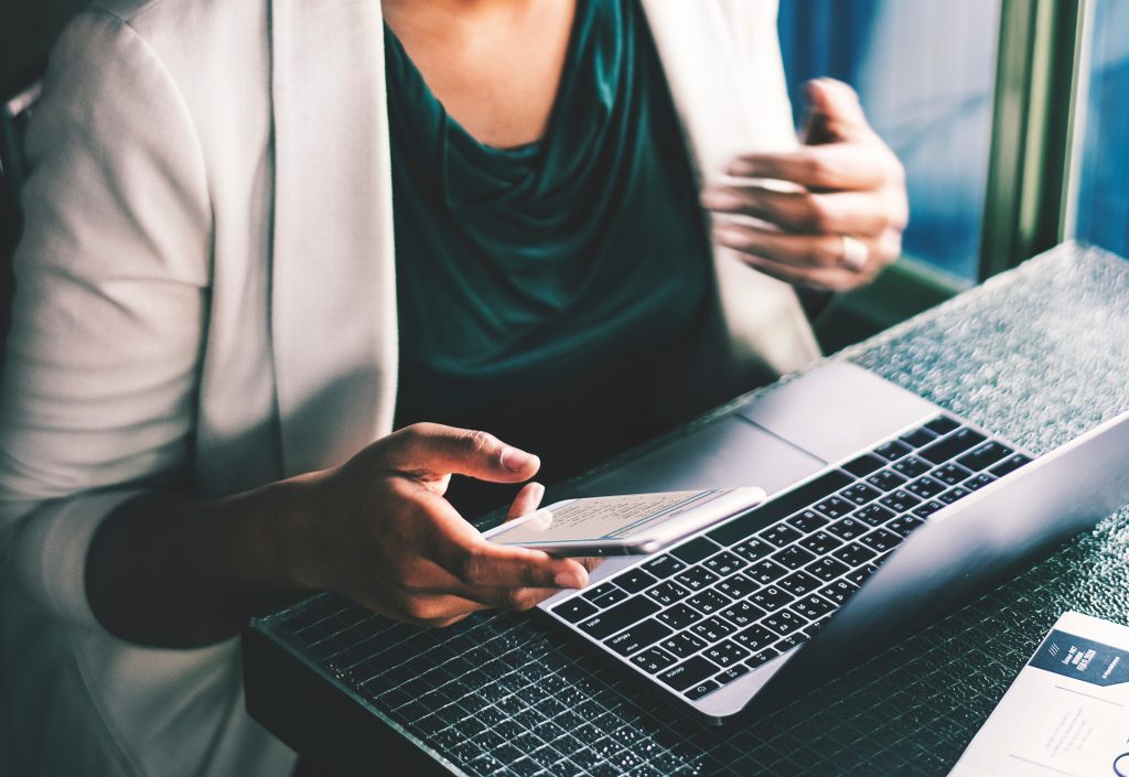 Business woman working on laptop with mobile phone